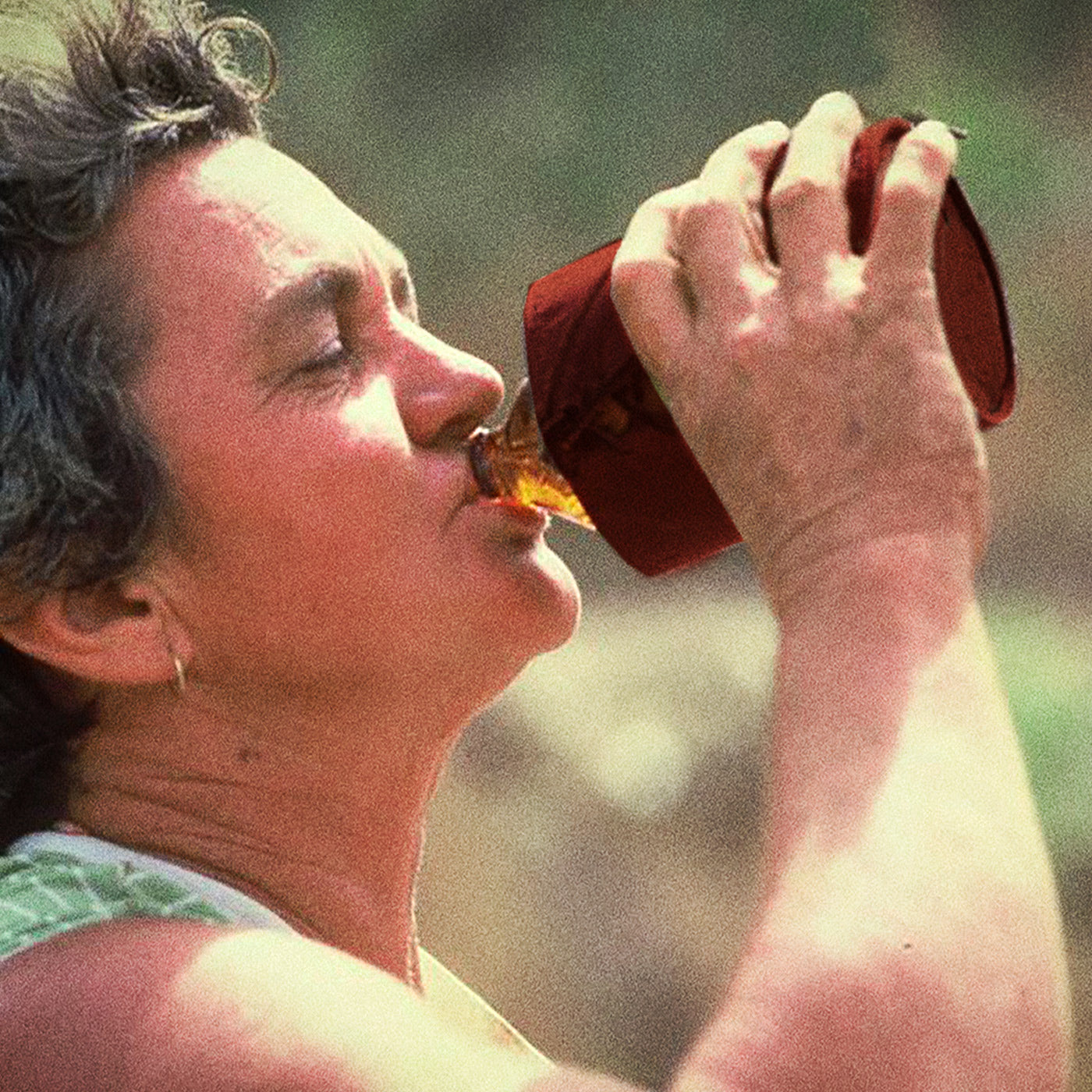 An older Australian lady drinking a beer from a stubby holder in rural Victoria