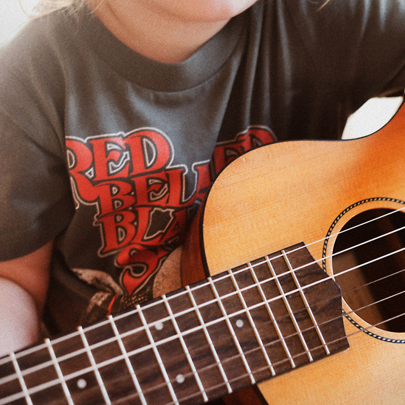 A child playing the guitar wearing The Beefs RBBS kids tee